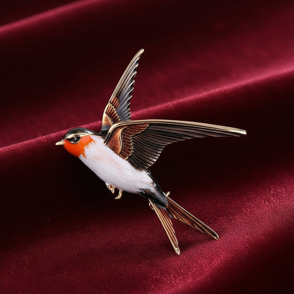 A colorful enamel bird brooch shaped like a flying swallow, featuring brown, white, and orange, with gold-tone metal accents, on a red background