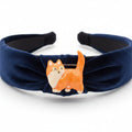 Small orange cat brooch pinned on a blue headband