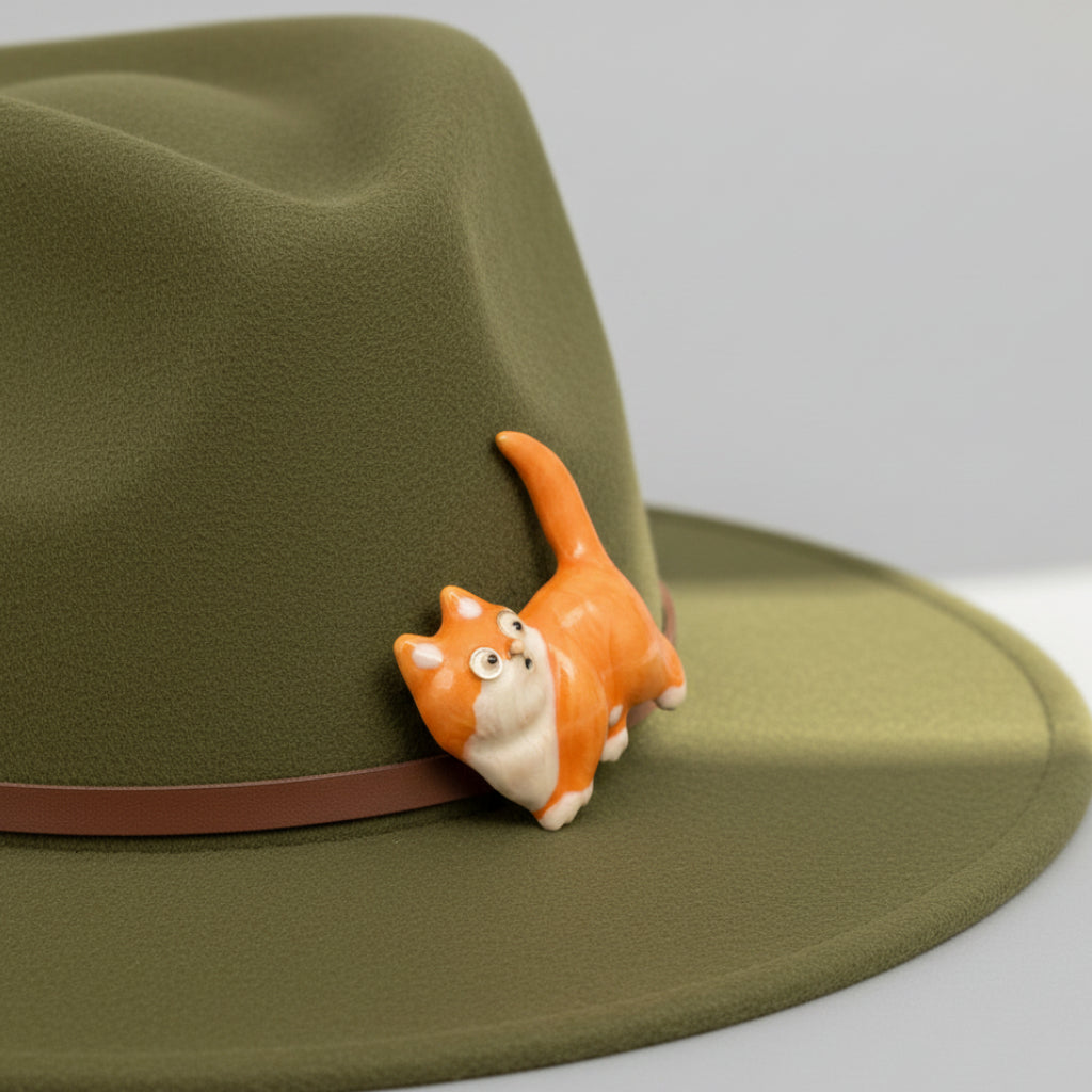 Small orange cat brooch pinned on a green hat
