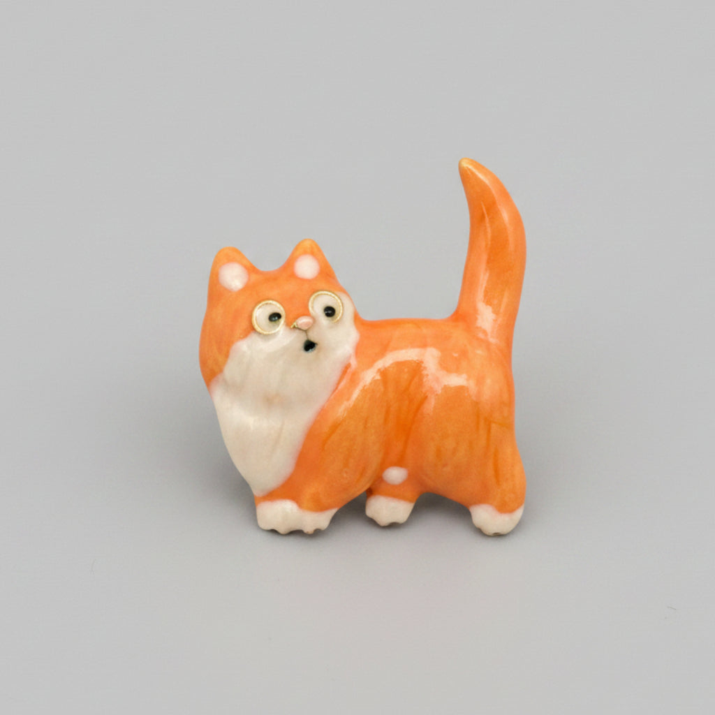 Small orange cat brooch on a gray background