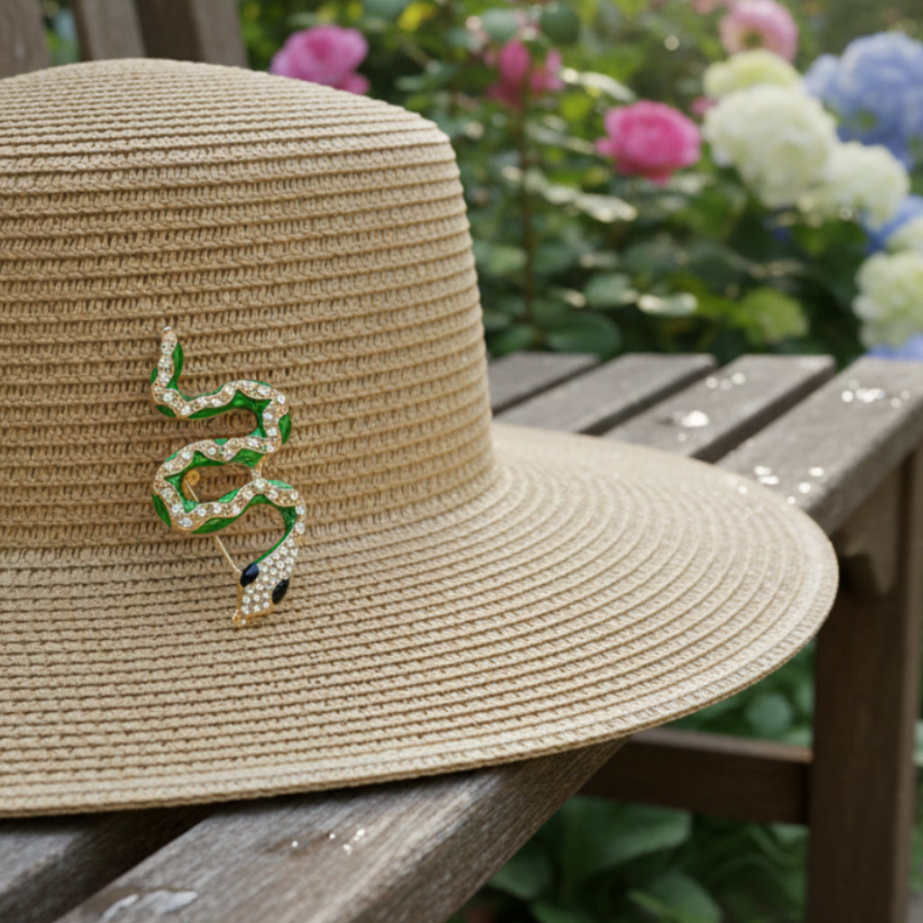Snake-shaped brooch with green and gold details pinned on a straw garden hat