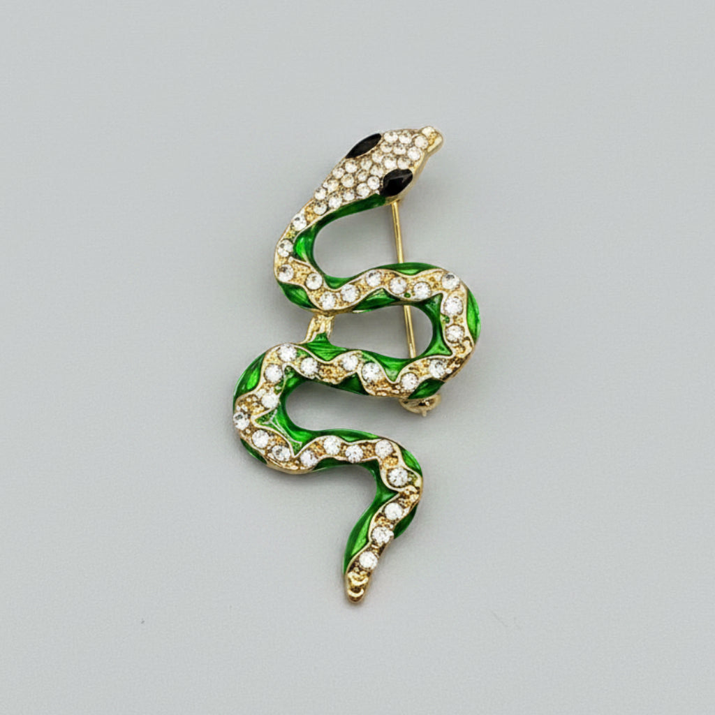Snake-shaped brooch with green and gold details on a gray background