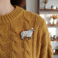 Sheep-shaped brooch made of pearls pinned on a yellow sweater