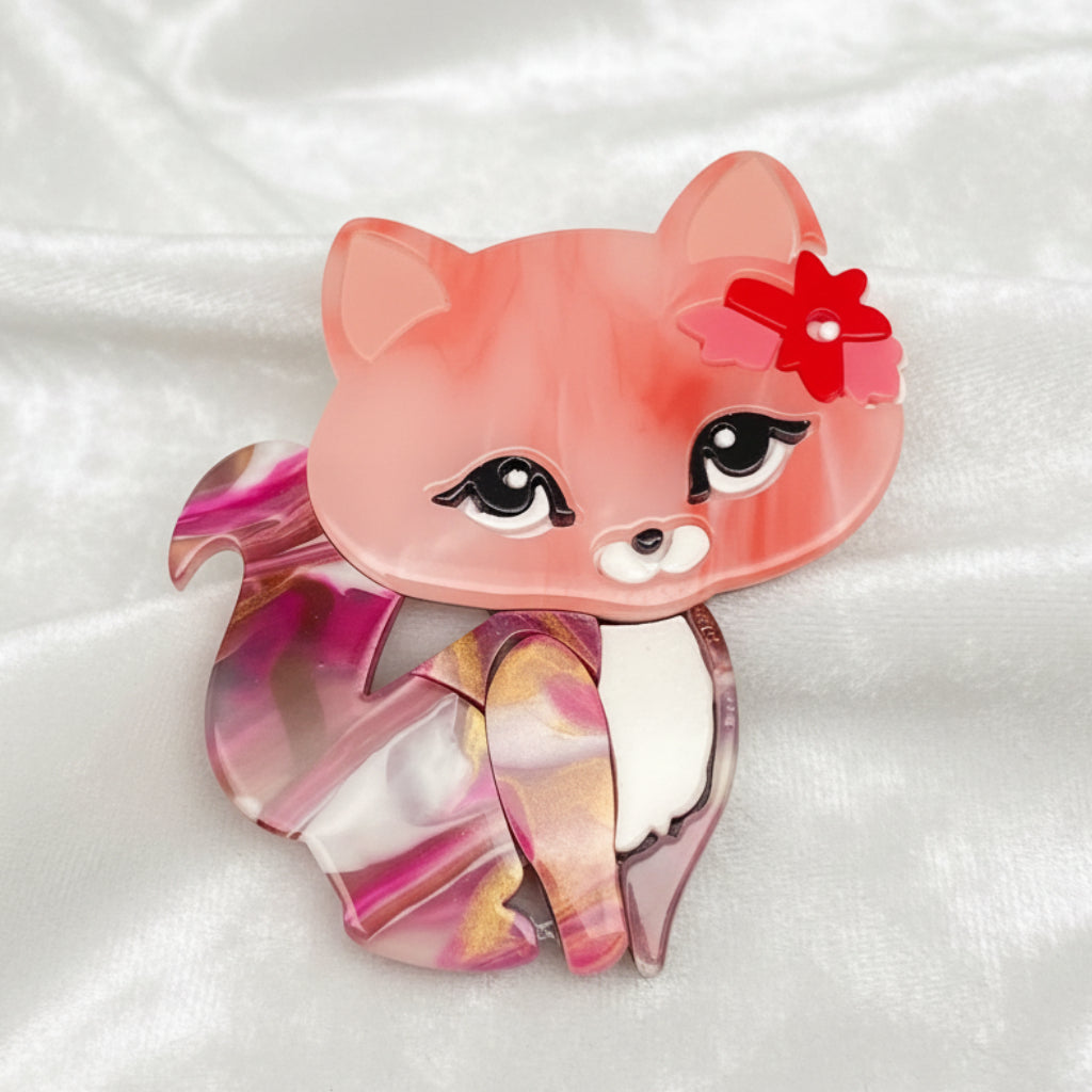 Pink cat-shaped brooch with a red flower on a white background