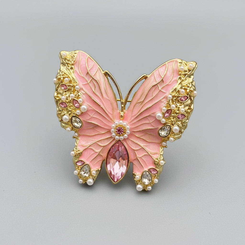 Butterfly-shaped brooch with pink center and gold and gemstone accents on a gray background