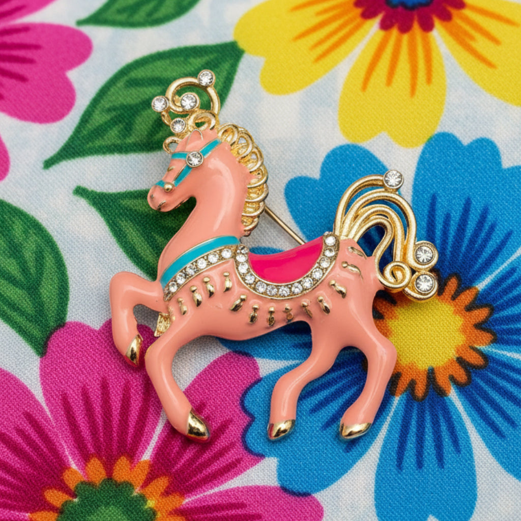 Decorative horse brooch with pink body, blue accents, gold mane and tail on a floral background