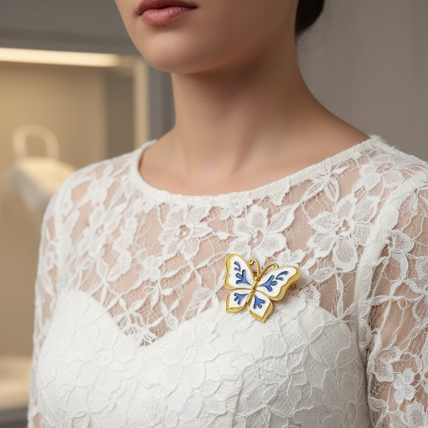 Butterfly-shaped brooch with blue and gold design on a white lace dress