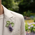 Brooch with green leaf design and purple glass stones, pinned on a linen jacket