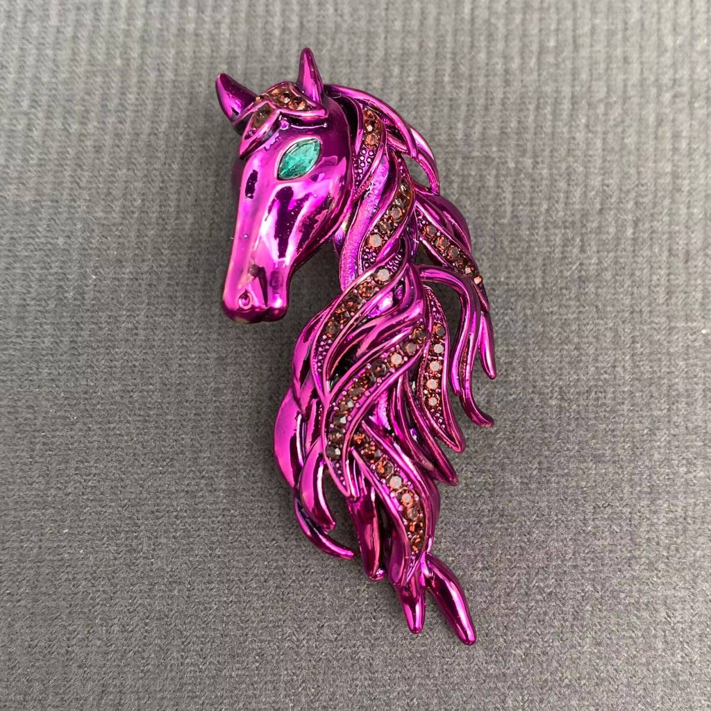 Purple horse-shaped brooch with gemstones on a gray background