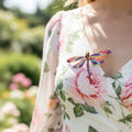 Colorful dragonfly-shaped brooch pinned on a floral dress