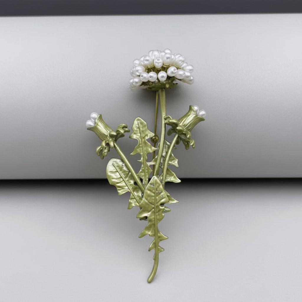 Dandelion brooch with pearl-like accents on a gray background
