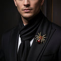 Gold spider-shaped brooch with red and black details pinned on a man's black suite