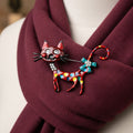 Colorful cat-shaped brooch pinned on a red scarf