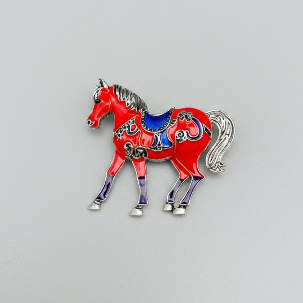 Red horse-shaped brooch with blue saddle on a gray background
