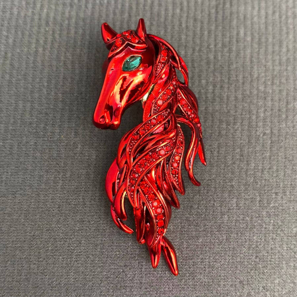 Red horse-shaped brooch with intricate details on a gray background