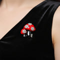 Red mushroom-shaped brooch with crystal accents on a black enamel stems