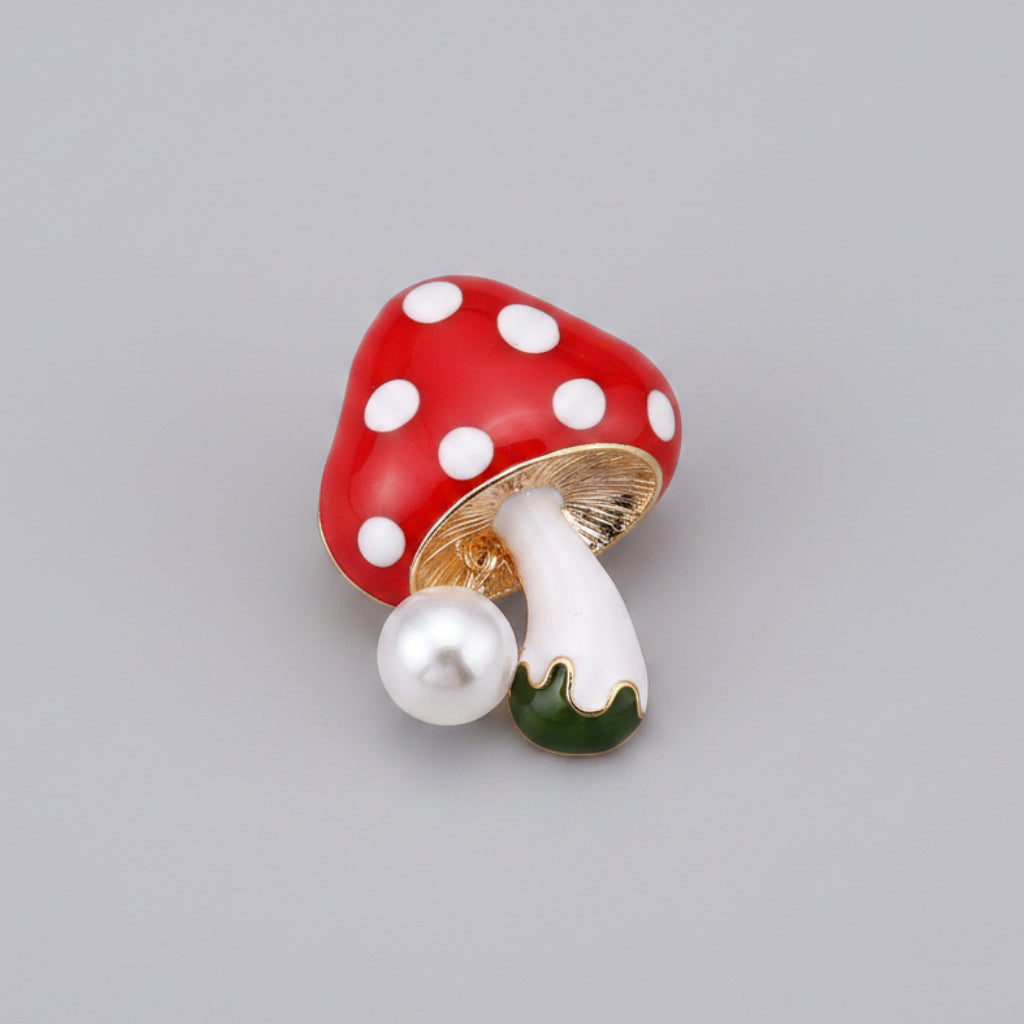 Mushroom-shaped brooch with red cap and white spots on a gray background