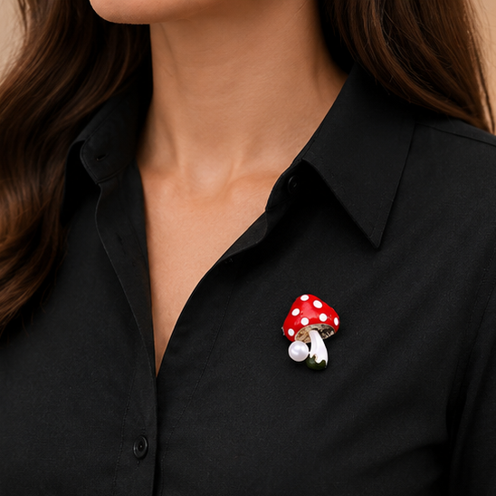 Mushroom-shaped brooch with red cap and white spots pinned on a black shirt