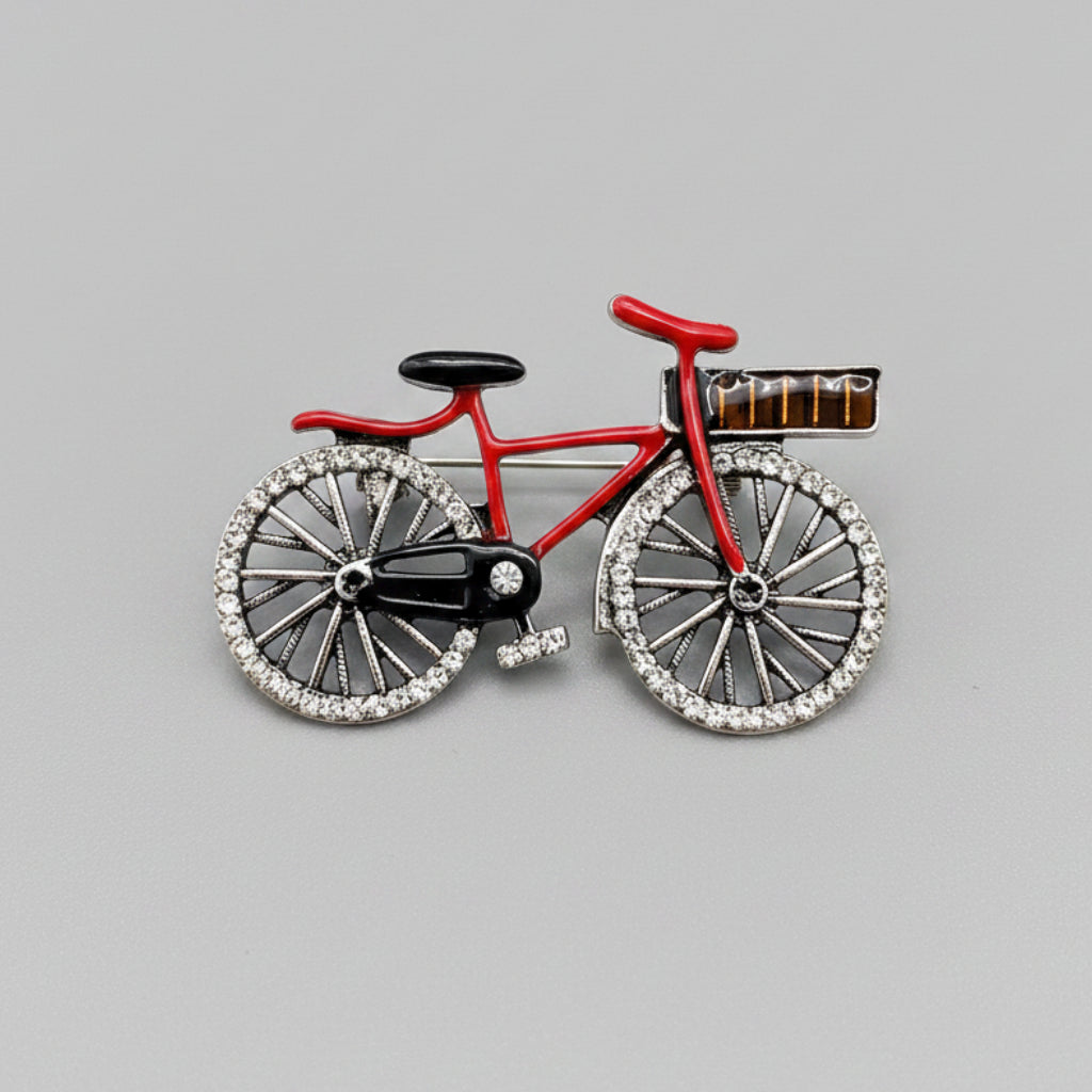 Bicycle-shaped brooch with red frame and black wheels on a gray background