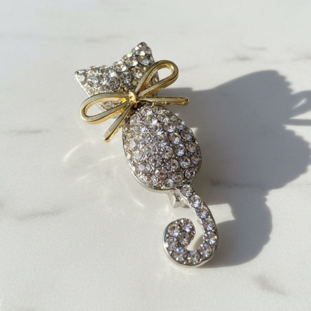 Cat-shaped brooch with rhinestones on a white marble background