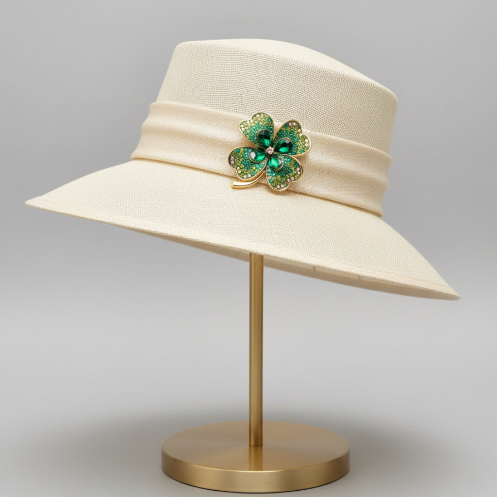 Green four-leaf clover brooch with gold accents pinned on a white hat