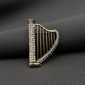 Harp-shaped brooch with rhinestone detailing on a gray background