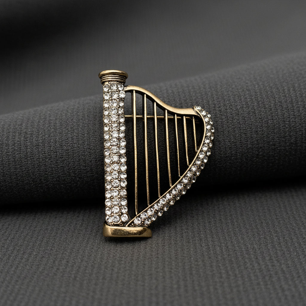 Harp-shaped brooch with rhinestone detailing on a gray background