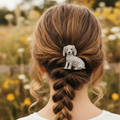 Silver dog-shaped brooch with gemstones on a gray background