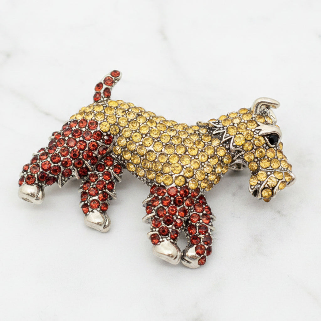 Dog-shaped brooch with yellow and red stones on a white background