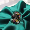Decorative zebra brooch with flowers on a green background