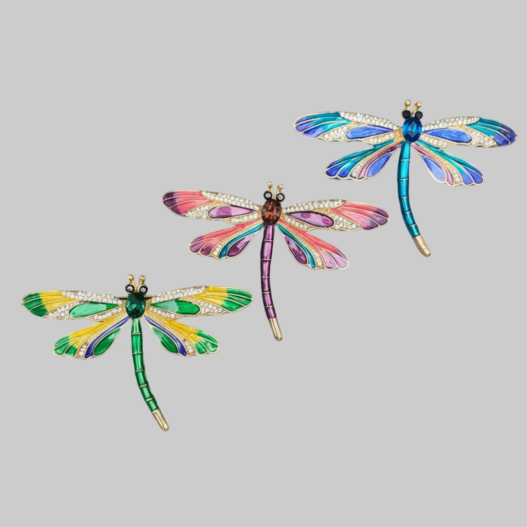 Three colorful dragonfly-shaped brooches on a gray background