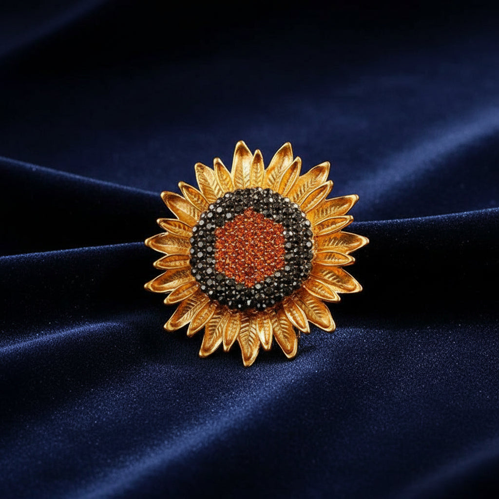Sunflower-shaped brooch with gold petals and gemstone center on a blue velvet background