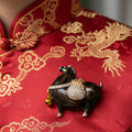 Brown Tang Dynasty-style horse brooch with a gold bell and rhinestone pouch pinned on a Oriental dress