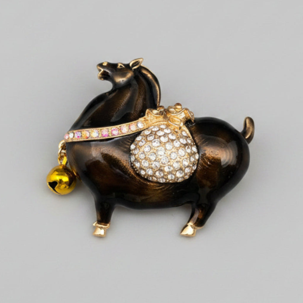 Brown Tang Dynasty-style horse brooch with a gold bell and rhinestone pouch on a gray 