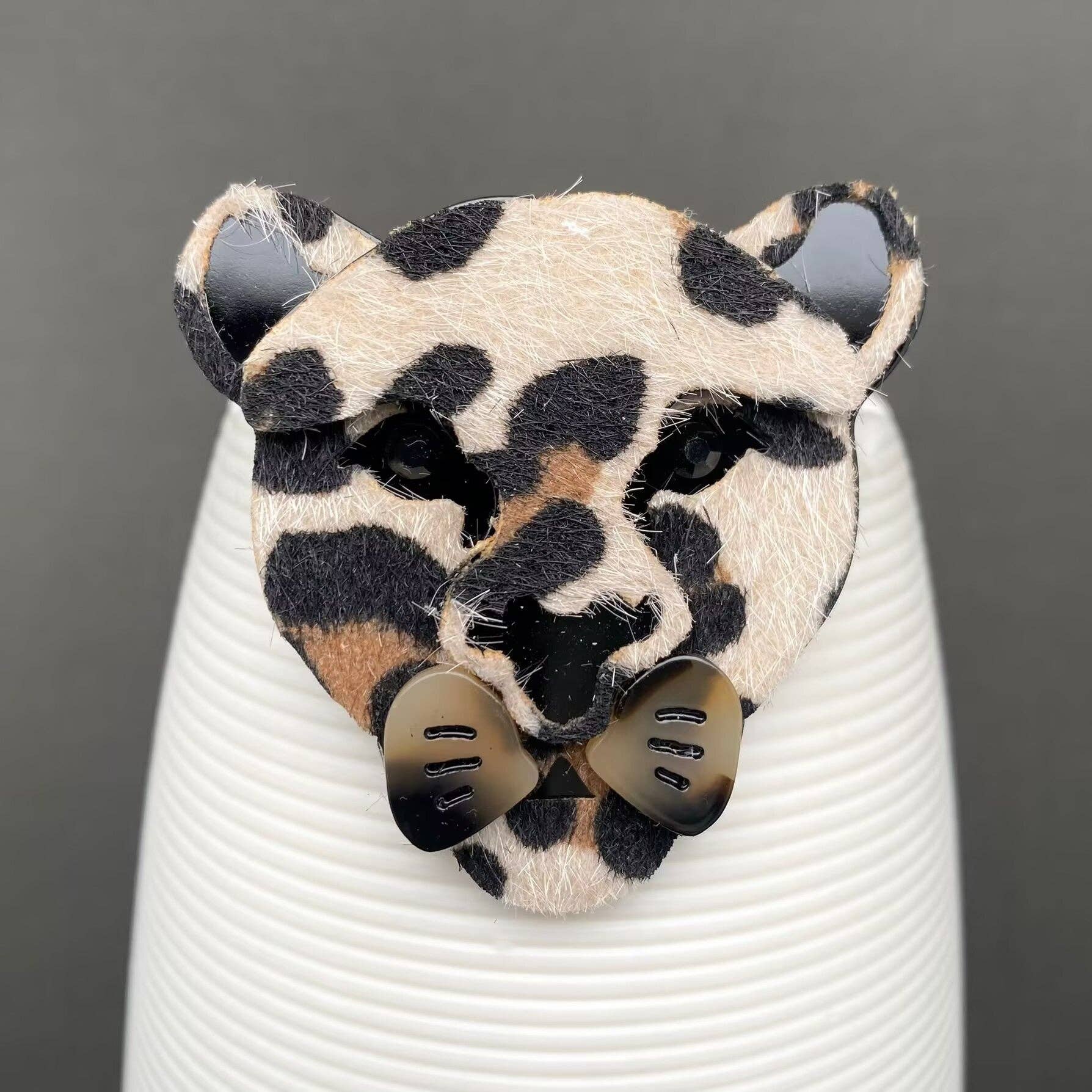 Textured acrylic leopard shaped brooch on a black background