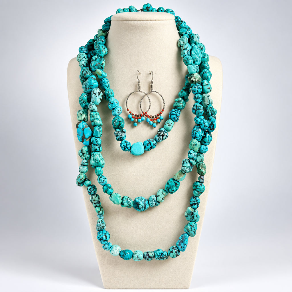 A jewelry set displayed on a beige mannequin bust, featuring a long multi-strand turquoise and blue-green stone necklace with matching beaded hoop earrings.