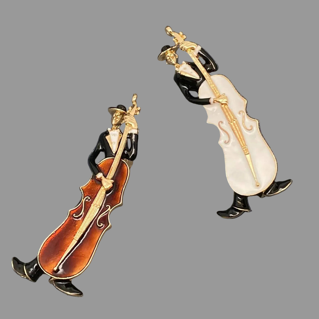 Two decorative pins of musicians playing cellos on a gray background