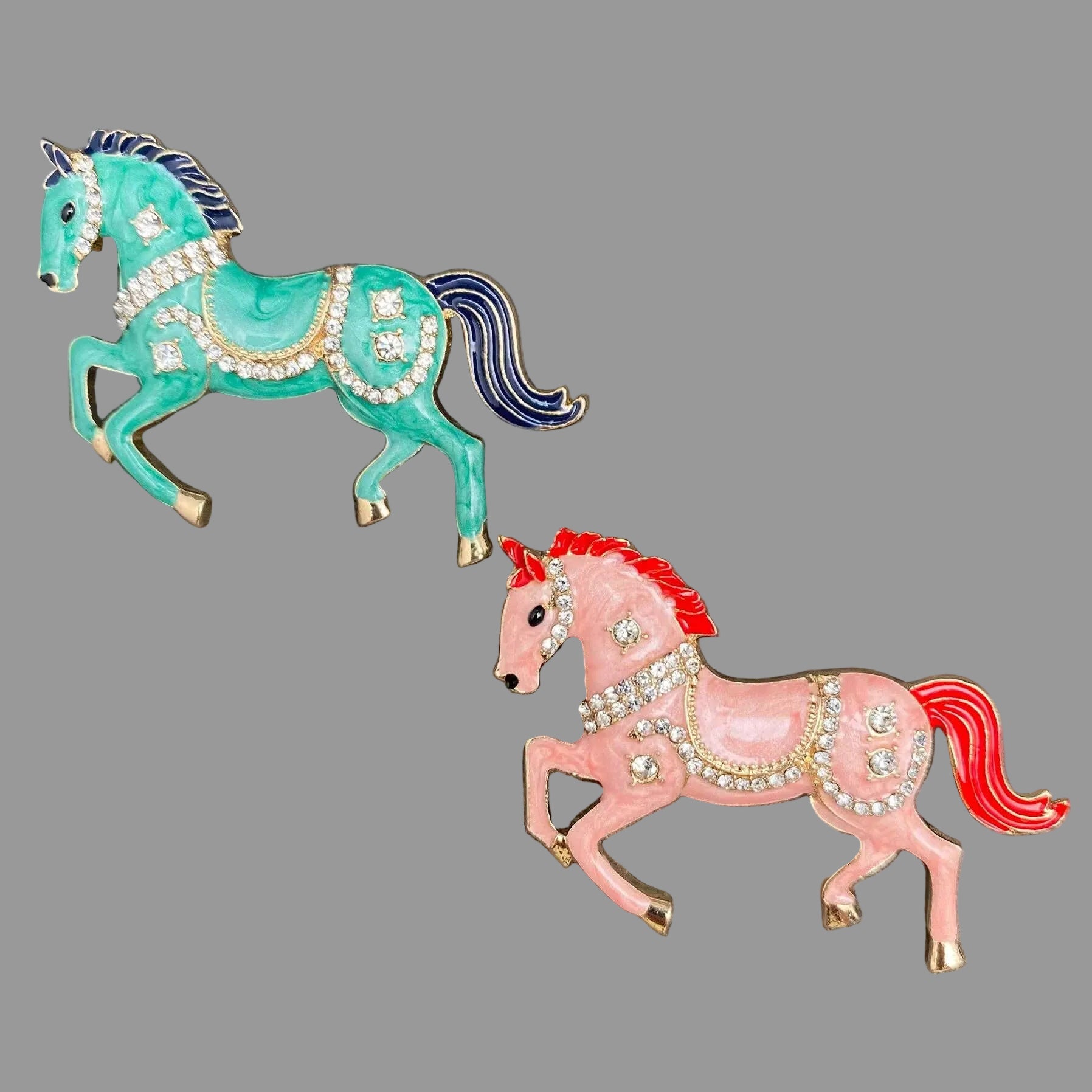 Two decorative horse pins, one green and one pink, on a gray background