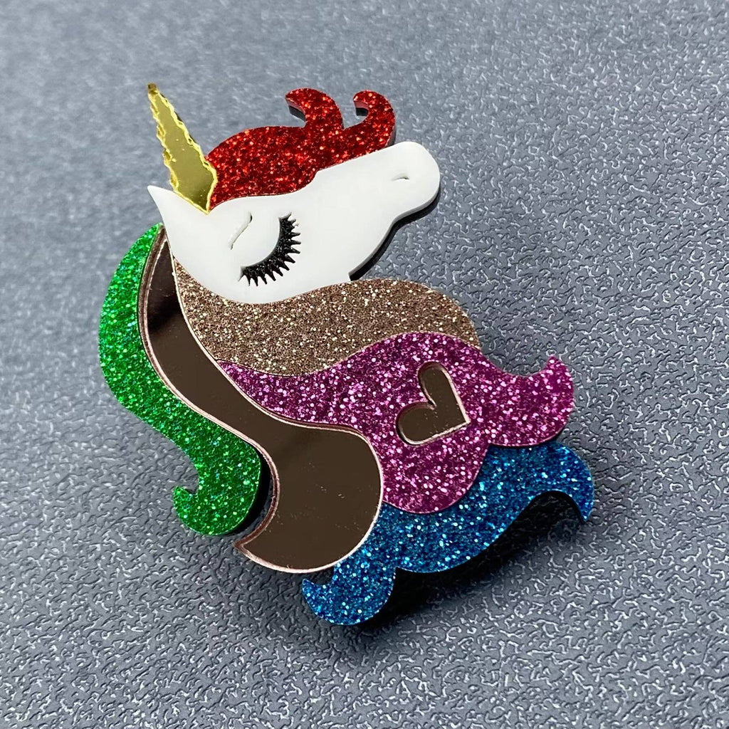 Glittery unicorn pin with multicolored mane and tail on a textured gray background