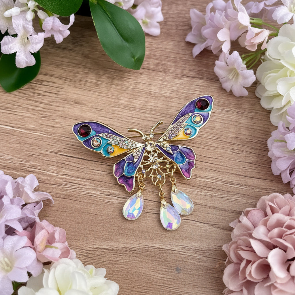 Colorful butterfly-shaped brooch with gemstones, on a wooden surface with flowers in the background
