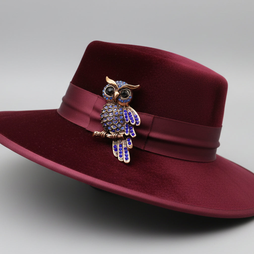 Decorative owl brooch with blue gemstones pinned on a red hat