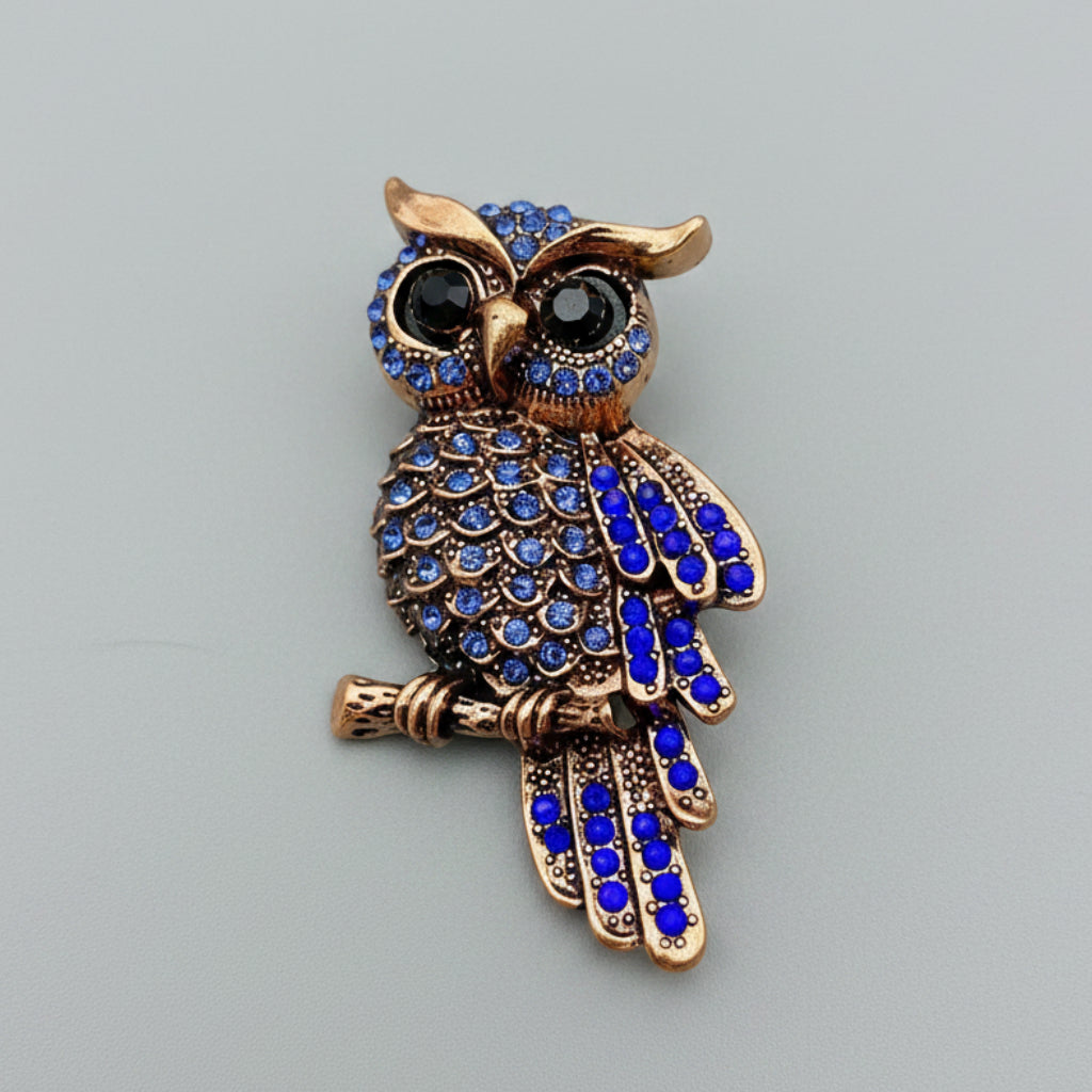 Decorative owl brooch with blue gemstones on a gray background