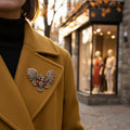 Vintage-inspired owl brooch pin with open wings, bronze detailing, and amber glass accents