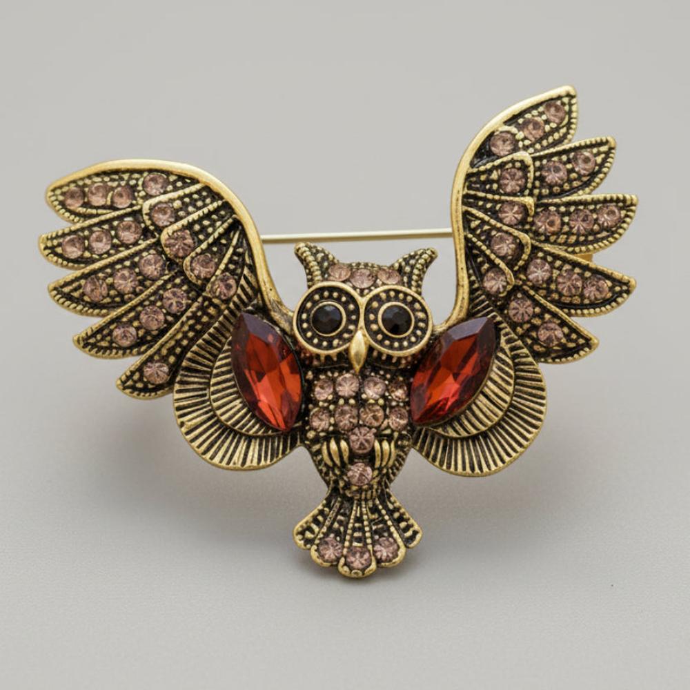 Vintage-inspired owl brooch pin with open wings, bronze detailing, and amber glass accents