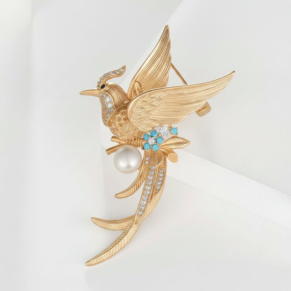 Gold phoenix brooch with pearls and gemstones on a white background