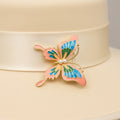 Butterfly-shaped brooch with pink, blue, and green wings on a white background