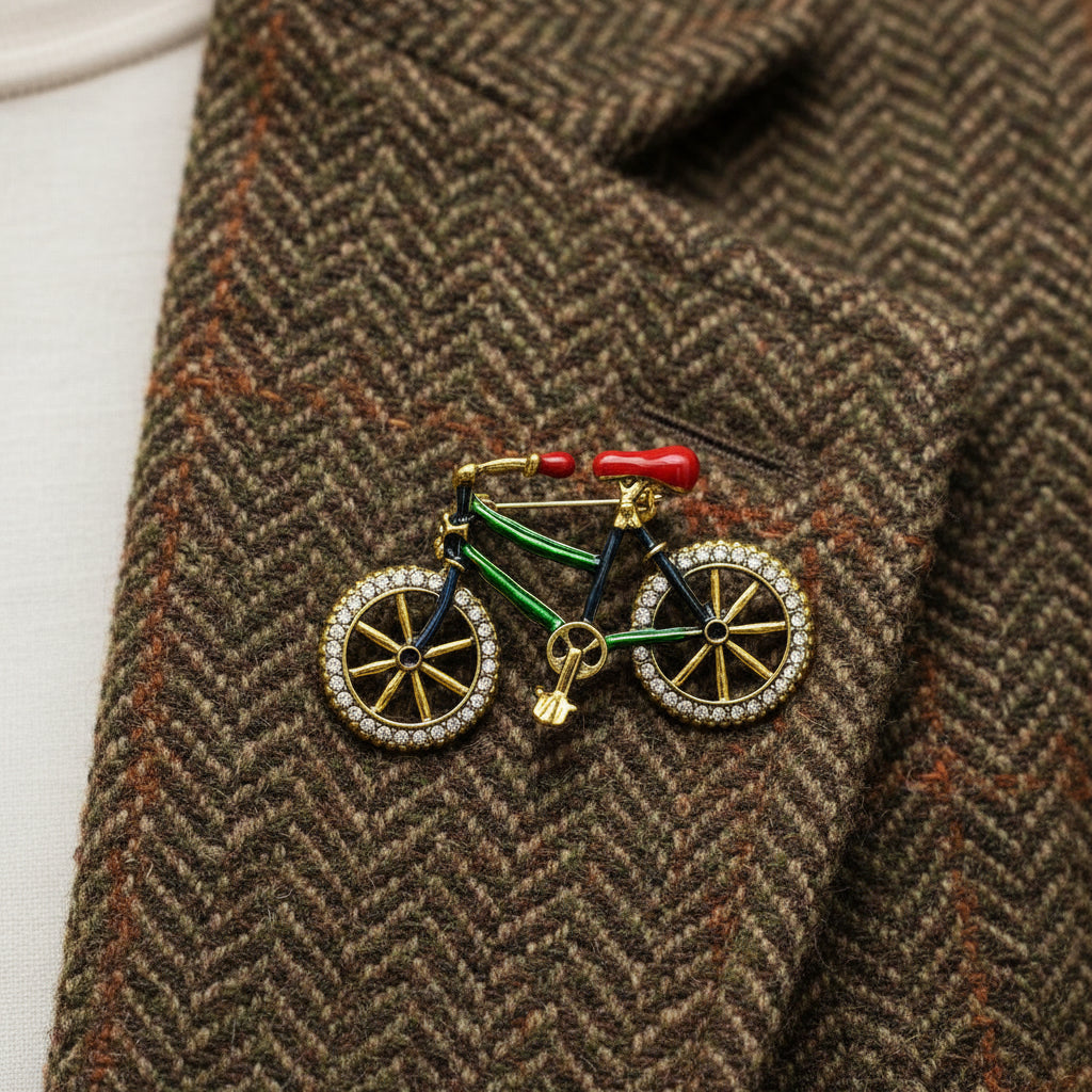 Bicycle-shaped brooch with gold frame, green body, and red seat pinned on a brown jacket