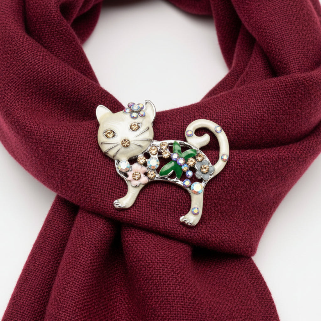 Decorative cat brooch with gemstones, pinned on a red scarf